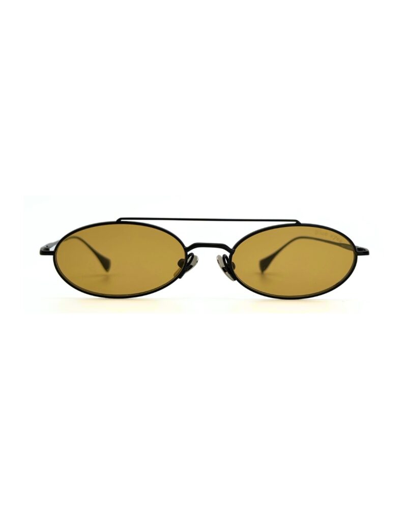 Homme au style urbain portant des lunettes de soleil BLUE EYES noires, monture fine à double pont et verres ambre clair.