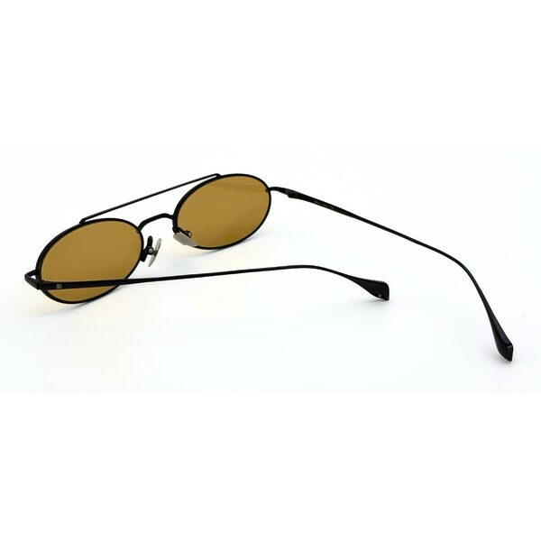 Homme au style urbain portant des lunettes de soleil BLUE EYES noires, monture fine à double pont et verres ambre clair.