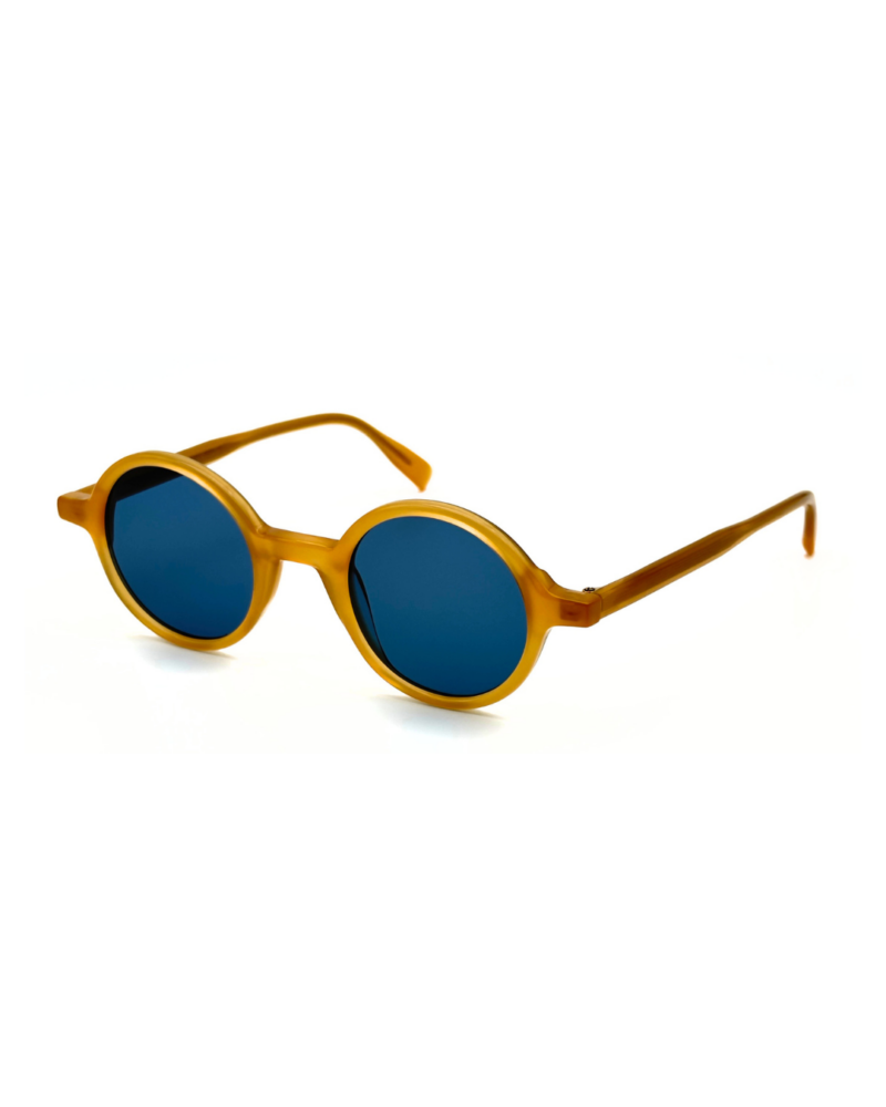 Lunettes de soleil rondes en acétate jaune miel Gigi Studios Greta avec verres bleus sous angle de trois quarts.