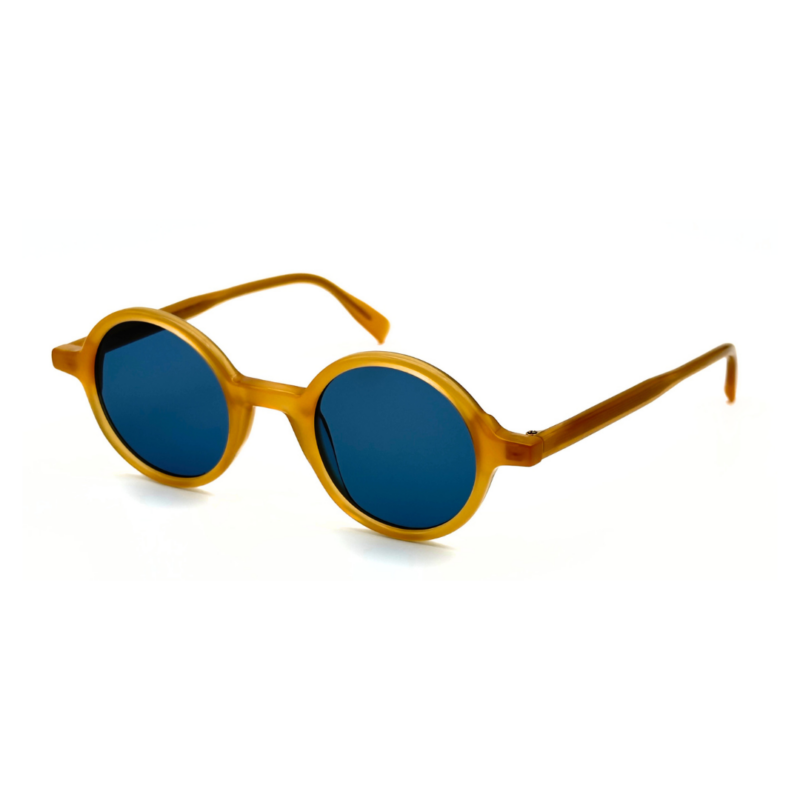 Lunettes de soleil rondes en acétate jaune miel Gigi Studios Greta avec verres bleus sous angle de trois quarts.