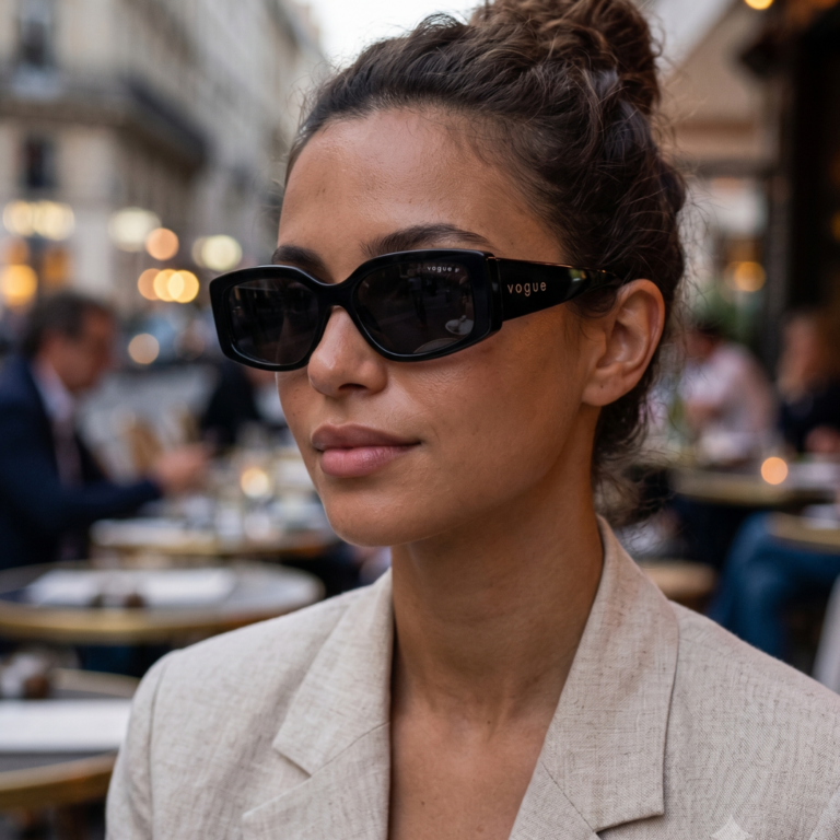 Femme portant les lunettes de soleil rectangulaires noir brillant Vogue VG5642SU W44/81 en terrasse de café avec un blazer