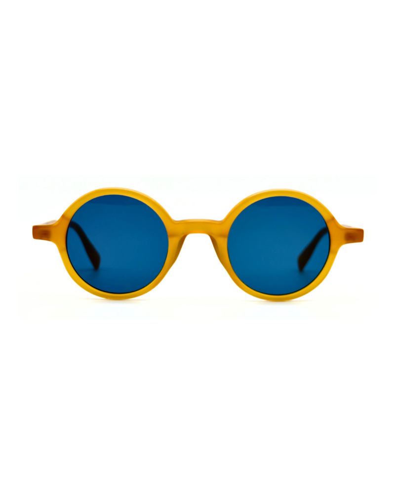 Lunettes de soleil rondes en acétate jaune miel Gigi Studios Greta avec verres bleus sous angle de trois quarts.