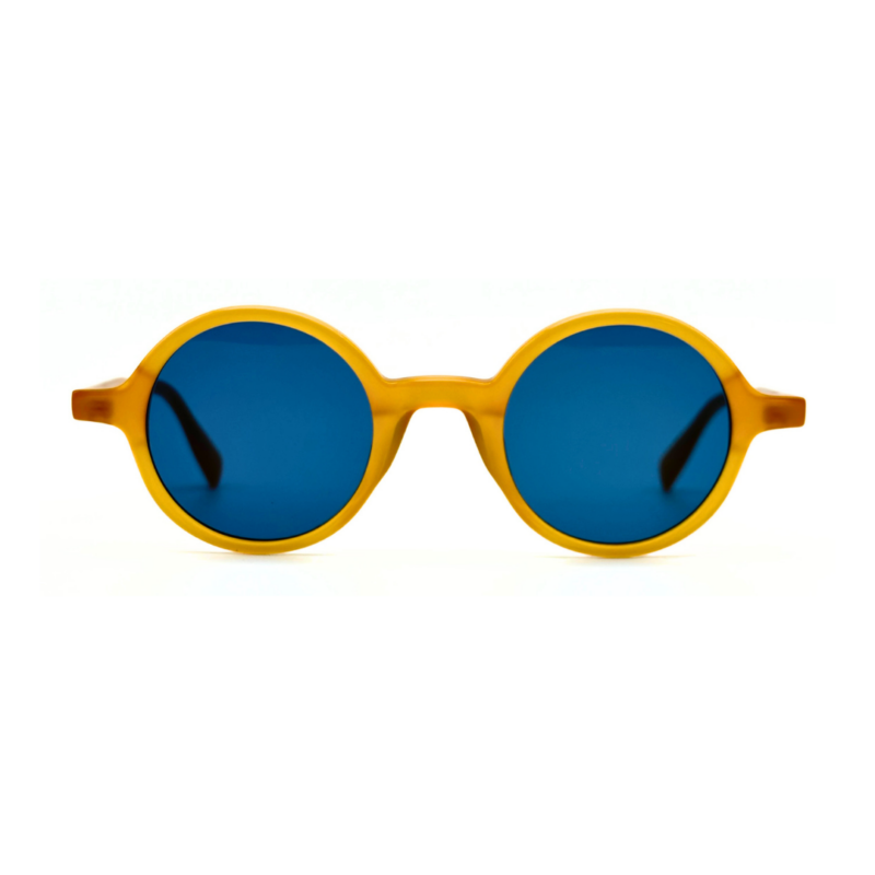 Lunettes de soleil rondes en acétate jaune miel Gigi Studios Greta avec verres bleus sous angle de trois quarts.