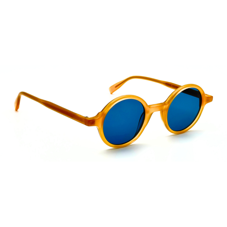 Lunettes de soleil rondes en acétate jaune miel Gigi Studios Greta avec verres bleus sous angle de trois quarts.