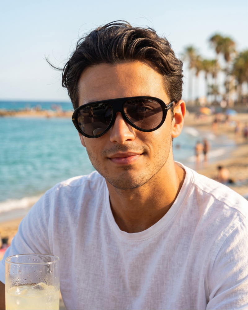 Jeune homme en t-shirt blanc portant les lunettes de soleil aviateur BLUE EYES AT1255 noires sur une plage en Tunisie.
