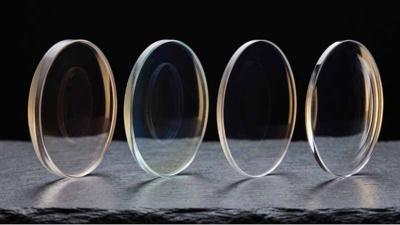 Quatre verres optiques d'épaisseurs et d'indices différents alignés sur fond noir